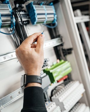 Akıllı bir ev elektrik kutusuna bağlanmış bir kabloya yakın çekim. Görüntü, gelişmiş ev otomasyon teknolojisini yansıtan ve kutunun içinde düzenli olarak düzenlenmiş karmaşık kablo detaylarını sergiliyor.