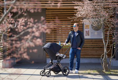 Bir babanın bahar yürüyüşü, bebek arabası ve çiçek açan manolyalar. Yüksek kalite fotoğraf