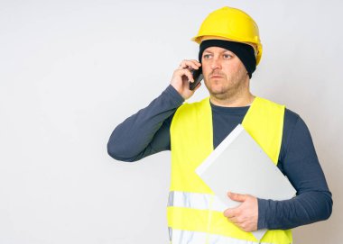 Sarı iş yeleği giyen, sarı kasklı, elinde cep telefonu olan bir adam. Yüksek kalite fotoğraf