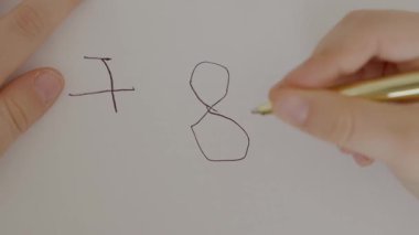 Bir çocuk rakamları beyaz kağıda yazmayı öğrenir, altın bir kalemi tutan bir çocuğun eline yakın plan yapmayı ve hayattaki ilk numaralarını yazmayı. Yüksek kalite 4k görüntü