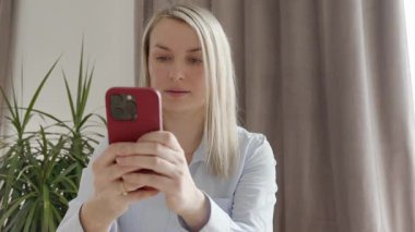 35-37 yaşlarında, Avrupa görünümlü, mavi tişörtlü, cep telefonuyla video görüşmesi yapan bir kız. Yüksek kalite fotoğraf