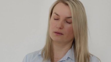 35-37 yaşlarında burnunu beyaz bir peçeteye silen bir kız, Avrupalı görünümlü, yakın plan, mavi gömlekli. Yüksek kalite 4k görüntü