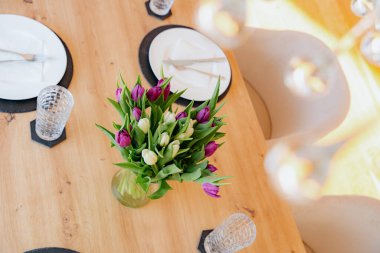 Tabaklar, bardaklar ve mor ve beyaz lalelerle dolu ahşap bir yemek masası manzarası. Sıcak, davetkar bir atmosfer yemek için yüksek kaliteli fotoğraf