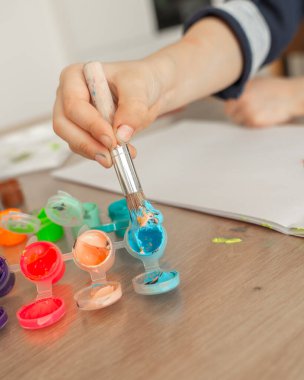 Erkek eli fırçayla bir sürü mavi renkli boya topluyor, 4-5 yaşlarında boyalı bir çocuk. Yüksek kalite fotoğraf