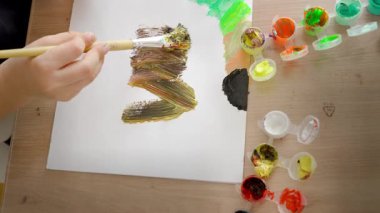 Çocuk bir palette boya karıştırıyor, 4-5 yaşlarında Avrupalı görünümlü bir çocuk evde boyalarla resim yapıyor. Yüksek kalite fotoğraf