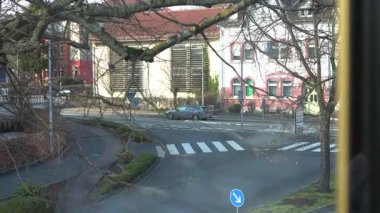 03.16.25 Bad Hersfeld, Almanya. Yol boyunca hareket eden küçük bir kavşağın yüksek açılı görüntüsü. Ağaç dalları ön planı çerçeveleyerek, kent sahnesine derinlik ve doğal bir dokunuş ekliyor