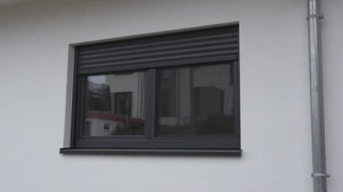 Evin pencerelerinin caddeye bakan tarafında otomatik panjurların inişini gösteren yatay bir video. Akıllı ev sistemi, panjurları, konforu ve modern yaşamı zahmetsizce kontrol eder..