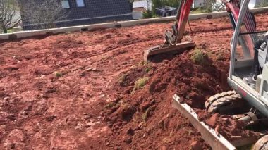 03.23.25 Bad Hersdfeld Almanya Kazıcısı elinde kovayla kil toprağı taşlarla tırmıklıyor. Ağır ekipmanlar inşaat sahasında aktif olarak çalışıyor, toprağı daha fazla inşaat çalışması için hazırlıyorlar.