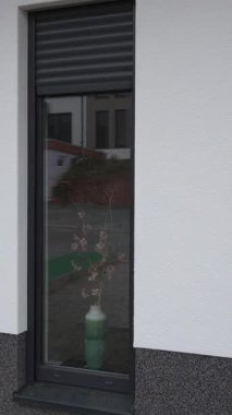 Evin pencerelerinin caddeye bakan tarafında otomatik perdelerin inişini gösteren dikey bir video. Akıllı ev sistemi, panjurları, konforu ve modern yaşamı zahmetsizce kontrol eder..