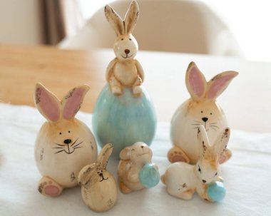 Oyuncak tavşanların seramik heykelcikleri çeşitli sevimli pozları gösteren bir masanın üzerinde toplandı. Düzenleme farklı boyut ve ifadeleri sergiliyor, Paskalya veya bahar dekorasyonu için mükemmel