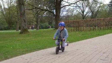 Bad Hersfeld, Almanya, 04.12.25 yaşlarında genç bir çocuk, yaklaşık 4 yaşında, hareket halindeki bir koşu bandında kayıyor, hızla yol boyunca ilerliyor, yeşillik ve neşe ile çevrili,