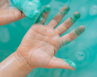 Suda sabunla oynayan bebek elleri, turkuaz suda sabunlu küçük ve büyük kabarcıklar, küvette, denizde..