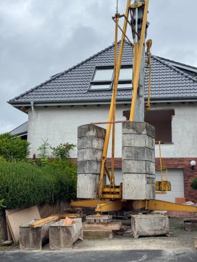 Bir evin yakınındaki yerleşim bölgesinde büyük bir sondaj kulesi var. Ağır inşaat görevleri için tasarlanan makine, kentsel kalkınma bağlamının merkezinde yer alıyor..