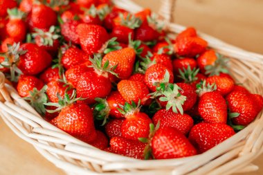 Parlak kırmızı çilekler hasır sepeti doldurur, tazeliklerini ve canlılıklarını sergilerler. Kompozisyon, doğal üretim temaları için mükemmel olan zengin renk ve dokuya vurgu yapıyor..