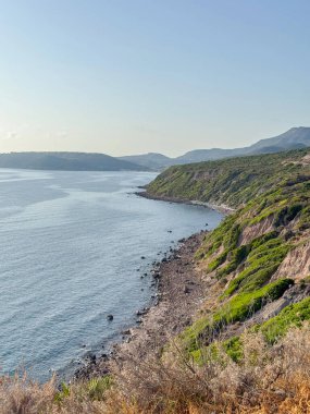 Yeşil uçurumları ve engin denizi olan engebeli bir sahil manzarası. Kaya ve yemyeşil bitki örtüsünün zıt dokuları büyüleyici bir doğal manzara oluşturur..