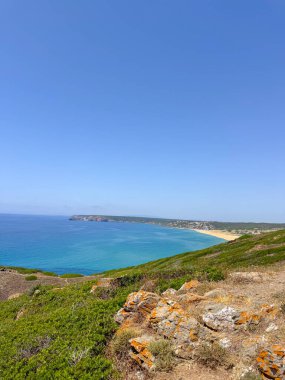 Uçurumlarla, berrak okyanuslarla ve mavi gökyüzünün altındaki uzak kıyılarla kıyı manzarası. Sahil arazilerinin ve sakin suların doğal güzelliklerini yakalıyor..