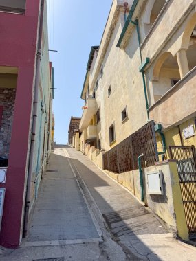 Sabit kentsel cadde, antika bir mahallede konut binalarıyla dolu. Dar yol çok katlı evler arasında yükseliyor, canlı şehir mimarisinin özünü yakalıyor..