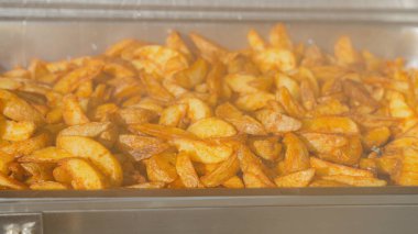 Baharatlı patates dilimlerini açık büfe ısıtıcısına koy. Sıcak, çıtır çıtır ve altın, yemek servisi, düğün menüleri, restoran promosyonları, yemek blogları ve ticari yemek fotoğrafçılığı için mükemmel..