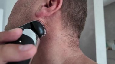 Yakın plan elektrikli tıraş makinesiyle tıraş oluyorum. Pazarlama kampanyaları, ürün ambalajlama, e-ticaret, erkek yaşam tarzı dergileri, berber hizmetleri veya ürün tanıtımları için ideal.