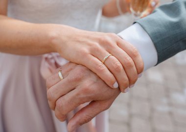 Dokunaklı bir düğün töreninde alyanslı ellerin yakın çekimi. Görüntü, yüzüklerin değiş tokuşuyla sembolize edilen samimi bağlantıyı ve bağlılığı yakalar..