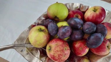 Elmalar ve erikler sanatsal olarak gümüş bir tepside sergilenerek taze meyve sergilenmesi için davet edilir. Canlı renkler ve zıt dokular doğal güzelliği ve tazeliği vurgular.