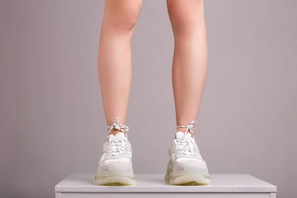 Sexy Piernas Zapatillas Blancas Sobre Fondo Gris Aislado — Foto de Stock