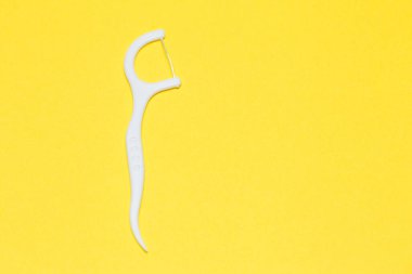 Plastic toothpick on a yellow isolated background. Hygiene and dental care.