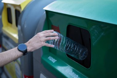 Adamın biri çöp kutusuna plastik şişe atıyor..