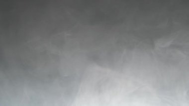 Gray smoke on a dark background, slow motion.