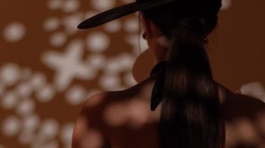 Fashion portrait of a girl in the studio with a black hat with golden decorations. Jewelry.