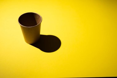 Sarı arka planda gölgeli karton kahve fincanı..