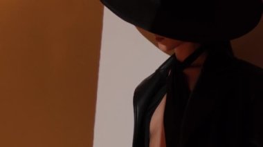 Fashion portrait of a girl in the studio with a black hat with golden decorations. Jewelry.
