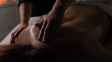 Massage of a female back in a dark room by candlelight close-up.