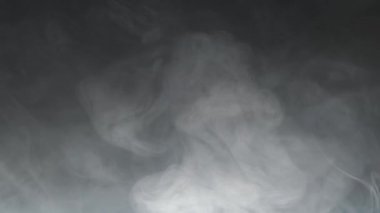 Gray smoke on a dark background, slow motion.