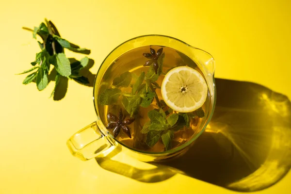 Green tea with lemon mint and star anise on a yellow background.