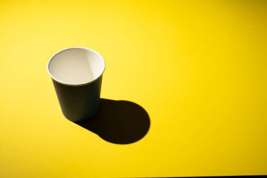 Sarı arka planda mavi kahve fincanı ve gölgesi var..