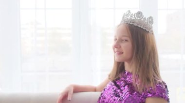 Kafasında taç olan şirin küçük bir prensesin portresi. Kız kameraya göz kırpar ve gülümser..