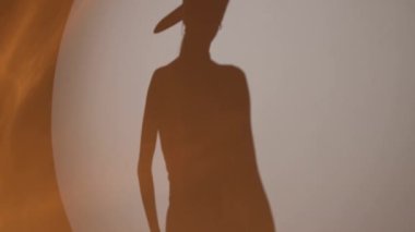 Silhouette of a girl in a hat on a white background in the studio.