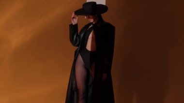 Fashion portrait of a girl in the studio with a black hat with golden decorations. Jewelry.