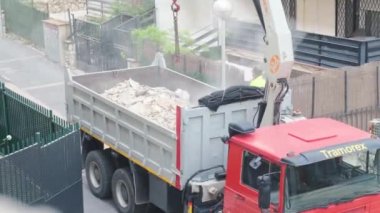 Tarragona, İspanya - 09 Mayıs 2023: Özel bir çantadaki asansör endüstriyel atıkları bir kamyona yüklüyor. Bir inşaat alanındaki çöpleri temizleme süreci.