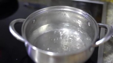 Elektrikli ocağın üstünde bir tencerede kaynayan su..