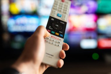Tarragona, İspanya - 20 Mayıs 2023: Bir erkek veya kadın televizyon kumandasındaki Netflix düğmesine basıyor.