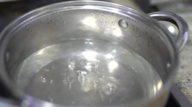 Elektrikli ocağın üstünde bir tencerede kaynayan su..