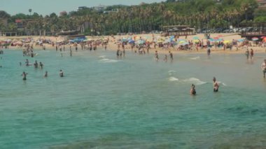 Tarragona, İspanya - 20 Ağustos 2022: Yazın deniz mevsimi. Tatilciler ve yüzücülerle dolu bir plaj..