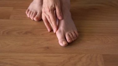 Hallux valgus, arka planda lamine döşeme üzerinde kadın bacakları. Bir kadının bacaklarında şişlik var. Yukarıdan görüntüle.