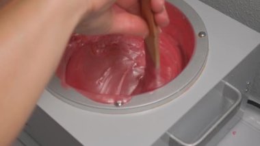 Sıcak balmumuyla karıştırmak. Tüy dökümü için erimiş balmumu. Balmumu spatuladan akıyor..