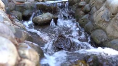 Derede kayalar, pürüzsüz akan su, yakın plan..