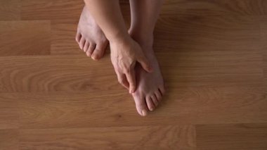 Hallux valgus, arka planda lamine döşeme üzerinde kadın bacakları. Bir kadının bacaklarında şişlik var. Yukarıdan görüntüle.