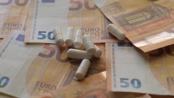 背景に50ユーロ紙幣 白い薬がある 製薬会社の概念は治療にお金を稼ぐ — ストック動画