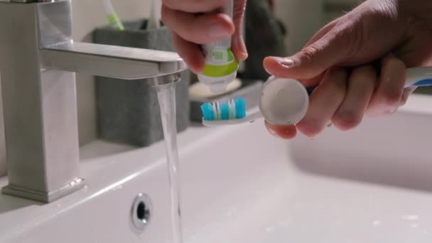 男性の目は ブラシのクローズアップにチューブから歯磨き粉を絞る — ストック動画